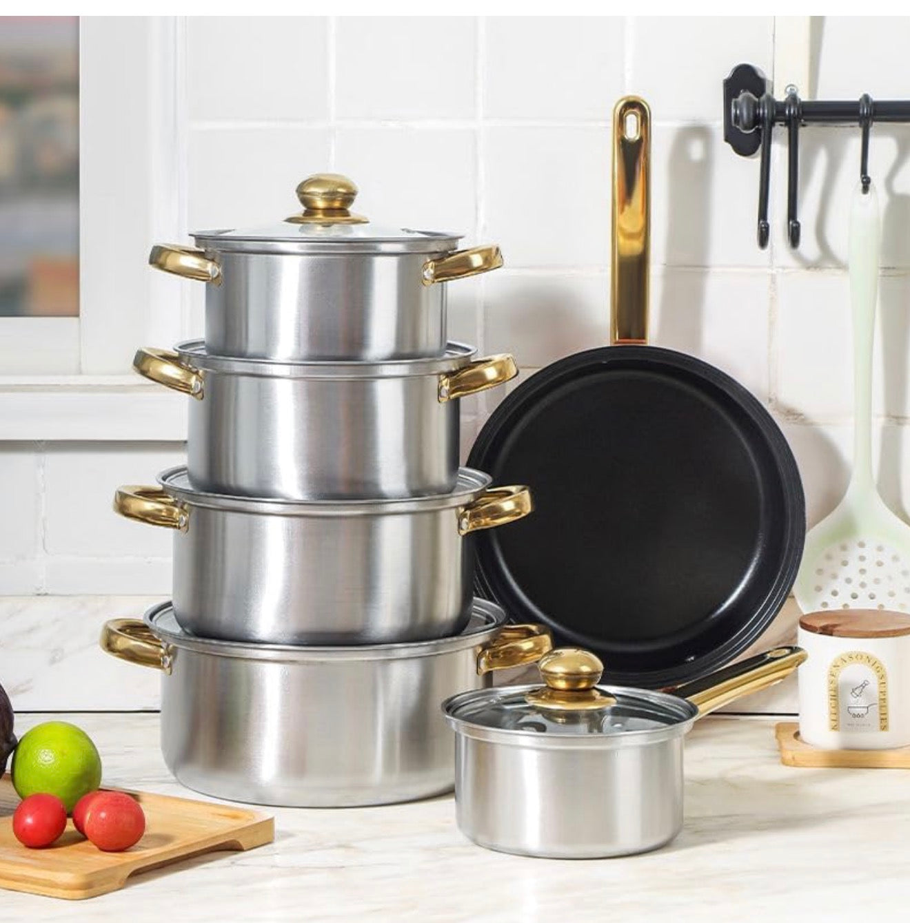 Set of stainless steel cookware with gold handles on a kitchen counter.